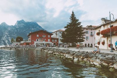 Houses by lake and buildings against sky