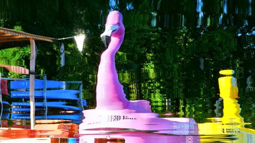 Midsection of woman with pink umbrella on railing