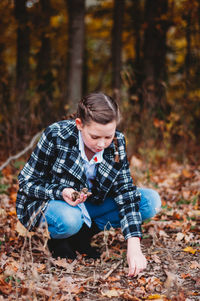 Teenage girl picking nuts on ground