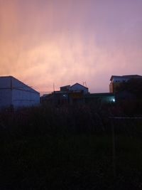 Houses on field against sky at sunset