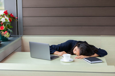 Young woman using laptop while sitting on table