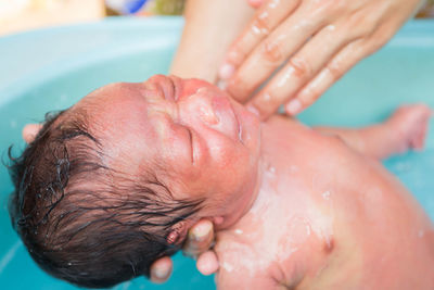 Cropped image of parent bathing newborn