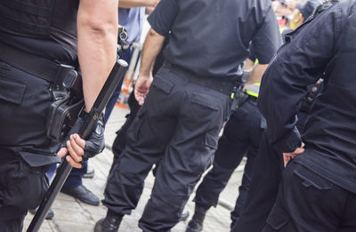 Midsection of police force standing on city street