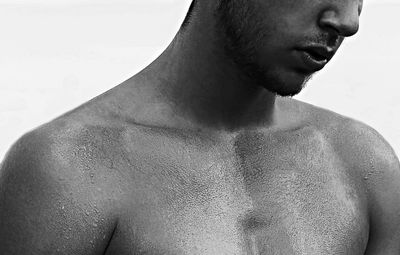 Close-up of shirtless man against white background