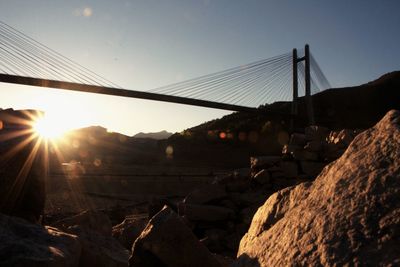 Suspension bridge over mountain against sky during sunset