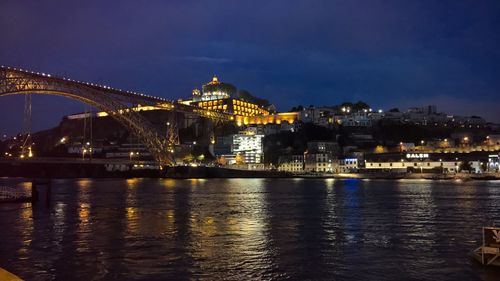 Illuminated bridge over river against sky at night