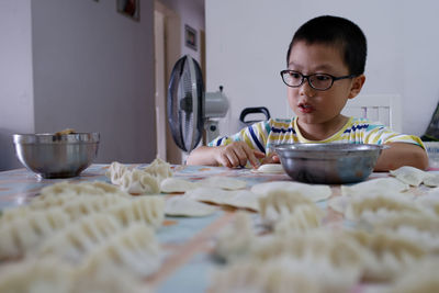 Boy making dumplings on table at home