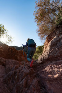 Woman climbs the mountain in the garraf natural park, supported by hiking sticks.