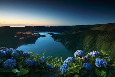 Scenic view of lake and mountains against blue sky