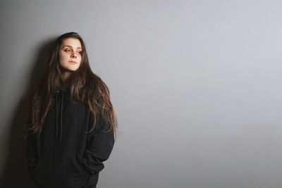 Portrait of beautiful young woman standing against white background