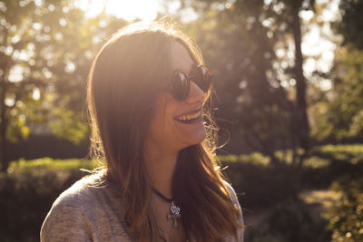 Smiling young woman looking away in park during sunny day