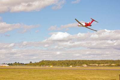 Airplane flying over field against sky