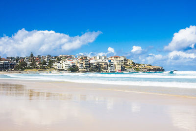 Buildings by sea against blue sky