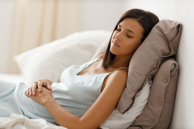 Portrait of young woman lying on bed at home