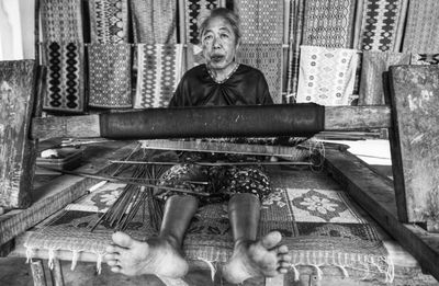 Portrait of smiling senior woman working on loom