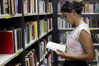 Portrait of beautiful girl standing in university library. searching information for a project