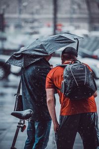 Rear view of people walking on wet road