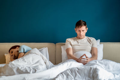 Thoughtful sad man woman in bed feeling feeling despair after quarrel at home.