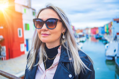 Portrait of young woman wearing sunglasses standing in city