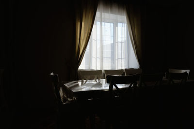 Empty chairs and table in dark room