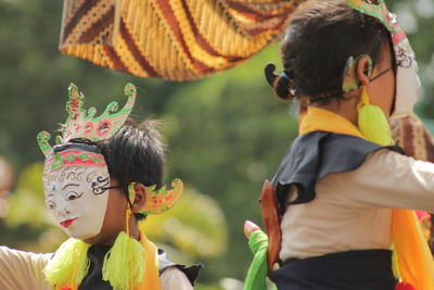 Side view of woman wearing mask and traditional clothing during festival