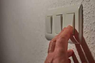 Close-up of person hand holding smart phone against wall