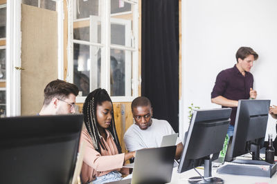 Team of confident young computer programmers working on new project in creative office