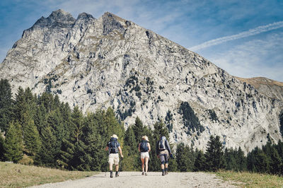 Rear view of people walking on mountain against sky