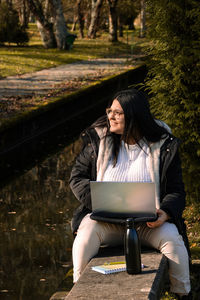 Woman working in the park with laptop. teleworking outdoors due to coronavirus. online business.
