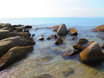 Rocks in sea against clear sky