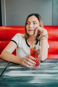 Portrait of smiling young woman drinking glass