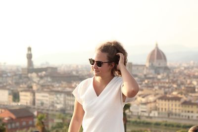 Young man wearing sunglasses standing against buildings in city