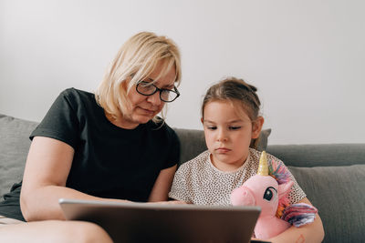 Woman assisting granddaughter using digital tablet at home