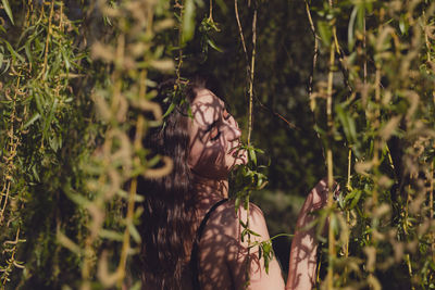 Portrait of young woman against plants