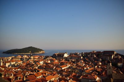 Town by sea against clear blue sky