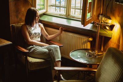 Full length of woman sitting on chair at home