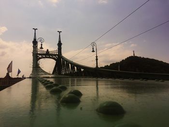 Bridge over river against cloudy sky