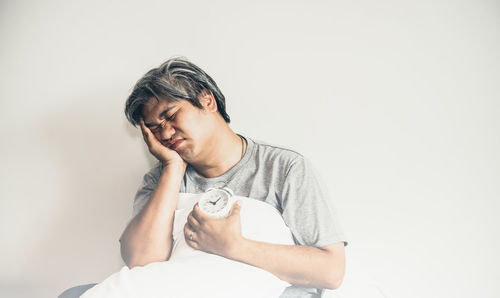 Portrait of young man sitting against white background