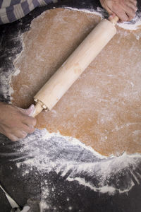 Cropped hands of person rolling dough on kitchen counter