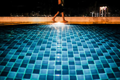 Low section of man walking on swimming pool