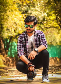 Portrait of young man wearing sunglasses sitting outdoors