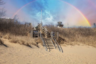 Rainbow over chatham lighthouse beach stairs on a sunny day in winter