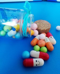 Close-up of multi colored pills on blue table