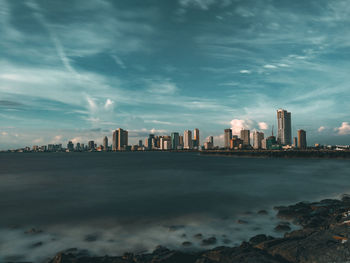 Sea by buildings against sky in city