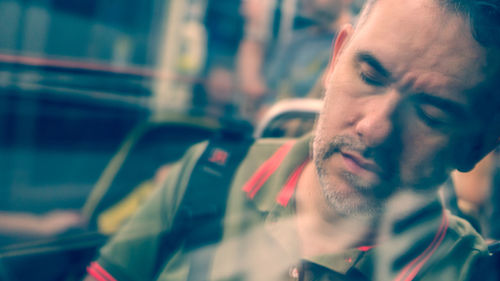 Man sleeping in bus seen through glass window