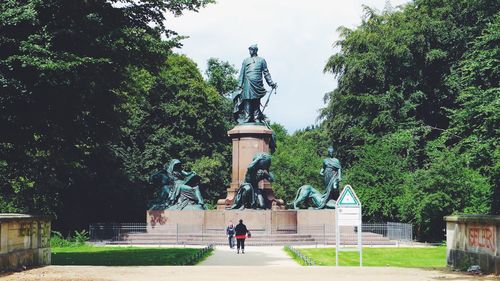 Rear view of man statue in park against sky