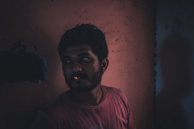 Portrait of young man standing against wall