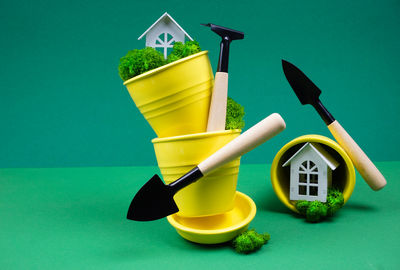 Creative photo on a green background with yellow flower pots and garden tools