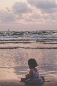 Rear view of boy looking at sea against sky