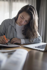 Young woman using mobile phone while sitting on table